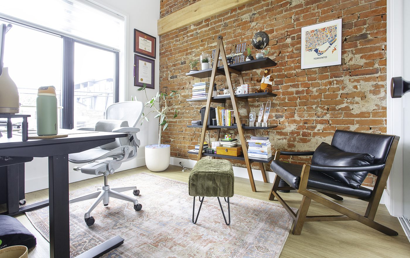 Bright room with an exposed brick wall, shelves, a desk and a reading chair